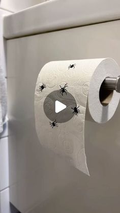 a roll of toilet paper with black bugs on it