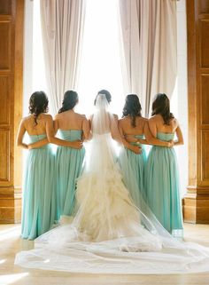 three women in long dresses are looking at each other while the woman is wearing a wedding dress