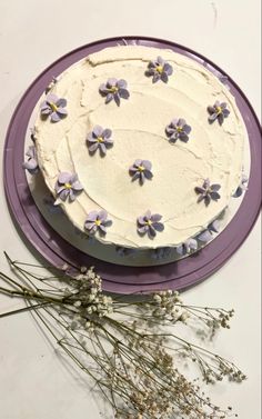 there is a cake with flowers on it and purple plate next to the frosting