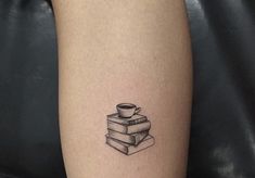 a black and white photo of a coffee cup on top of two books with a stack of books behind it