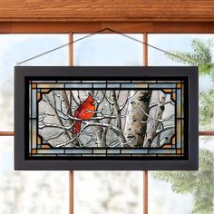 a stained glass window with a cardinal perched on a tree branch in front of it