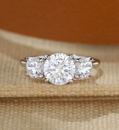 three stone diamond ring setting on top of a piece of cloth with wood in the background