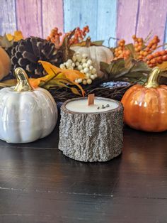 a candle sitting on top of a wooden table next to pumpkins and other decorations