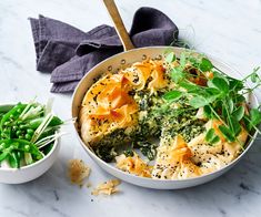 a white bowl filled with food next to some green vegetables