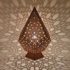 an intricately designed lamp is shown against a white wall with shadows from the ceiling