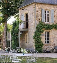 an old stone house with ivy growing on it's side and tables set up outside