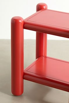 a small red table with two shelves on each side and one shelf below the top