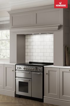 a stove top oven sitting inside of a kitchen next to white cupboards and drawers