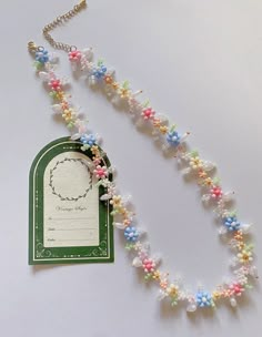 a necklace that has flowers on it and a tag attached to the beaded chain