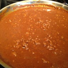 a pan filled with red sauce sitting on top of a stove