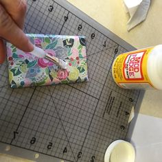 a person is cutting fabric with scissors and glue on the table next to a piece of cloth