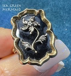 Welcome to Sea Green Mermaid! For sale is a 10k yellow gold onyx signet ring with a diamond forget-me-not. This Victorian era mourning ring has wonderful gothic styling. I had my jeweler make this ring from a brooch so it would be worn and enjoyed. The ring has a large rectangular 10k gold frame with elegantly scalloped edges. The onyx is decorated with a silver forget-me-not flower set with tiny rose-cut diamonds. The flower is lovely, with a curving stem and a pin-wheel style flower. Each leaf Forget Me Not Ring Gold, Black Victorian Signet Ring Collectible, Forget Me Not Ring, Luxury Antique Cameo Signet Ring, Antique Cameo Signet Ring Collectible, Onyx Signet Ring, Pin Wheel, Jelly Opal, Forget Me Not Flower