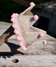 a pair of shoes with pink pom - poms are sitting on a piece of wood