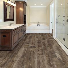 a large bathroom with wooden floors and white walls, along with a walk in shower