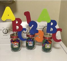 three jars with magnets and letters on top of a table