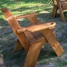 two wooden chairs sitting on top of a grass covered field