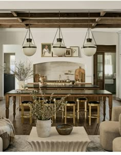 a dining room table with chairs and pictures on the wall above it in an open living area