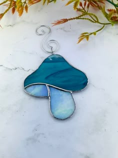 a blue and white stained glass piece hanging from a metal hook on a marble surface