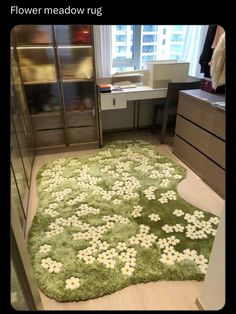 a green rug with white flowers on it in front of a dresser and window sill