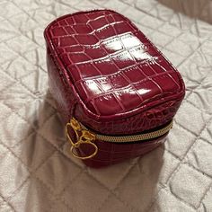 a small red purse sitting on top of a white bed next to a pair of scissors