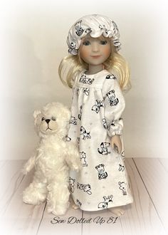 a doll and a white teddy bear on a wooden floor