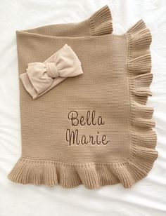 a crocheted blanket with a bow on it and the word bella marie written in black ink