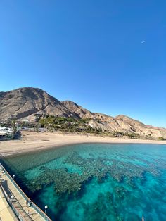 the water is crystal blue and clear with mountains in the background