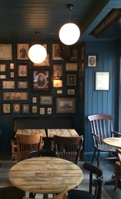 the interior of a restaurant with wooden tables and chairs, framed pictures on the wall