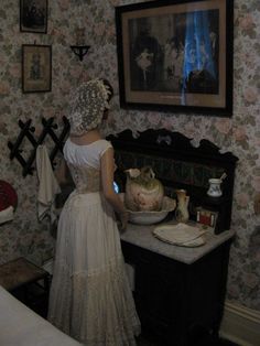 a woman standing in front of a table with a cake on it and an old fashioned tea kettle