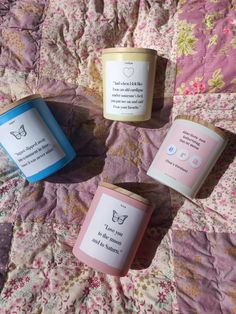 three candles sitting on top of a bed covered in pink and blue sheets, next to each other