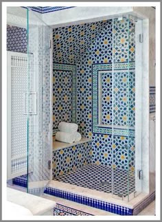 a bathroom with blue and white tiles on the walls, shower stall and countertop