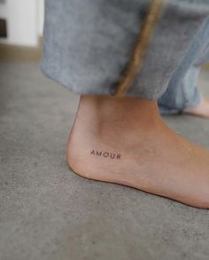 a person's foot with the word amour written on it, in front of their feet