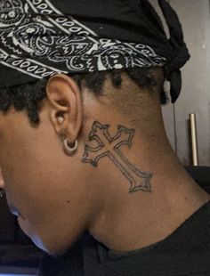 a man with a cross tattoo on his neck and behind his ear, wearing a black t - shirt