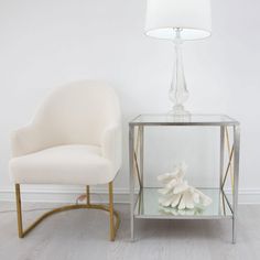 a white chair sitting next to a glass table with a stuffed animal on top of it