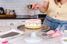 a woman is decorating a cake with sprinkles