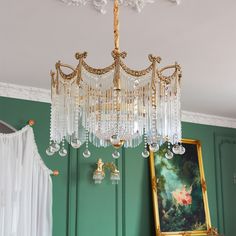 a chandelier hanging from the ceiling in a room with green walls and white curtains