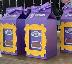 three purple boxes with yellow frames on them are sitting on a table in front of balloons