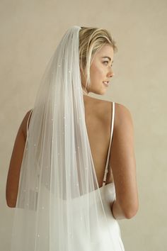 a woman in a wedding dress is looking back at the camera while wearing a veil