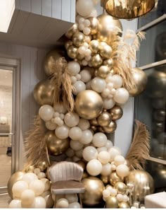 a bunch of balloons hanging from the side of a wall next to a chair and table