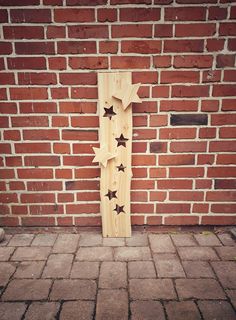 a wooden cross on the side of a brick wall with stars cut out of it