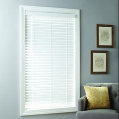 a living room with two framed pictures on the wall and a window covered in blinds