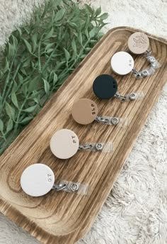 four wooden keychains sitting on top of a wooden tray next to some green plants