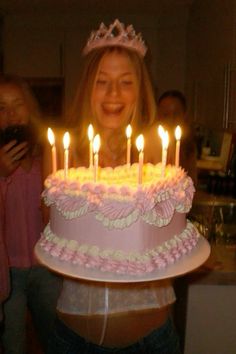 a woman holding a cake with lit candles on it