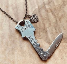 a necklace with a heart shaped key and a knife hanging from it's side