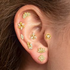 a woman's ear with gold and diamond studs on her left side, in the shape of flowers