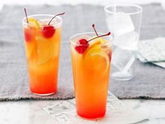 two glasses filled with drinks sitting on top of a table