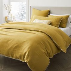 a bed with yellow linens and white pillows