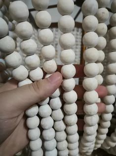 a person is holding some white beads in their hand