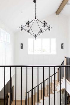 a chandelier hanging from the ceiling in a room with white walls and wood floors