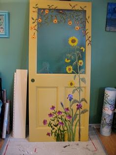 a door with flowers painted on it in front of a blue wall and other items